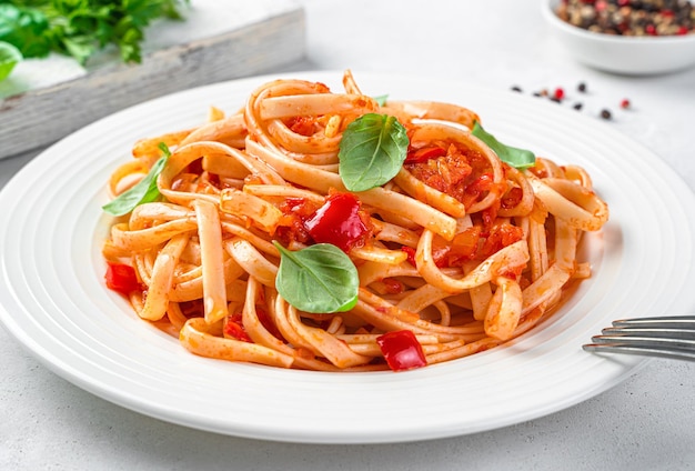 Italian pasta with tomatoes and basil closeup on a light gray background