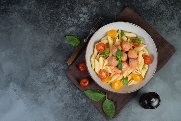 Italian Penne pasta with meatballs, tomatoes and aromatic herbs