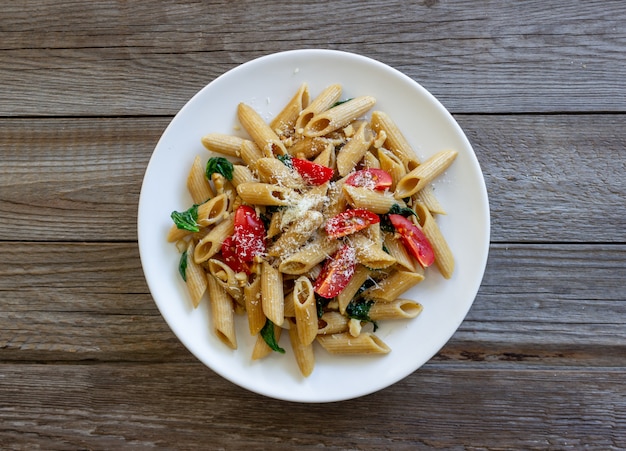 Italian penne pasta with tomatoes, spinach, parmesan cheese, garlic and nuts. Healthy eating. Vegetarian food.