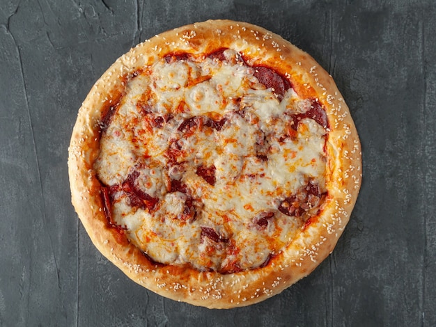 Italian pepperoni pizza. With pepperoni sausage, tomato sauce, Mozzarella cheese, Sulguni and Parmesan. Wide side. View from above. On a gray concrete background. Isolated.