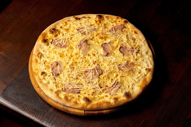 Italian pizza carbonara with bacon and cheese on a wooden board. Italian cuisine. Close-up