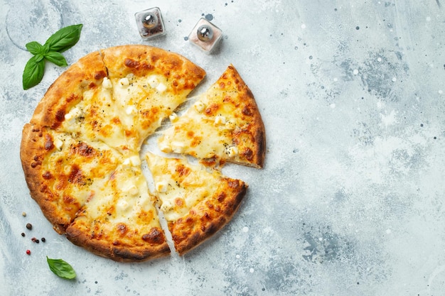 Italian pizza four cheeses with stretching cheese and basil on a light concrete background