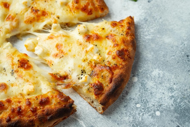 Italian pizza four cheeses with stretching cheese and basil on a light concrete background