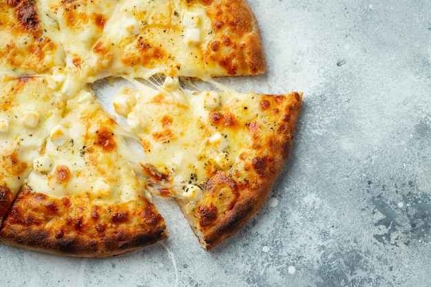 Italian pizza four cheeses with stretching cheese and basil on a light concrete background