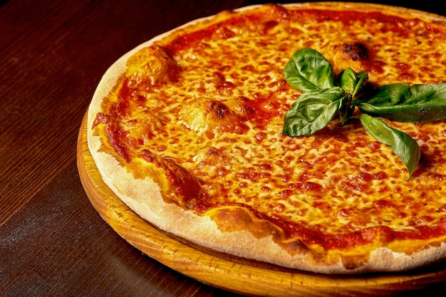 Italian pizza Margherita with tomatoes and cheese on a wooden board. Italian cuisine. Close-up