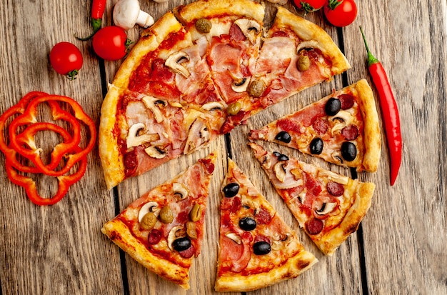 italian pizza with bacon, mushrooms, olives, tomatoes on a wood background