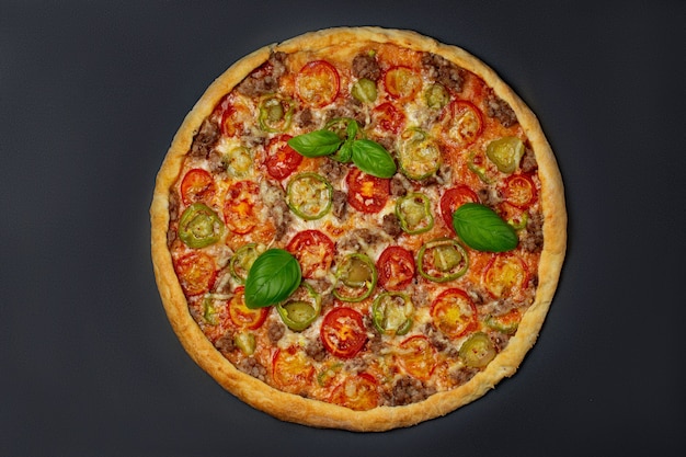 Italian pizza with melted mozzarella cheese and tomatoes, pepper garnished with fresh leaves basil on a thick crust