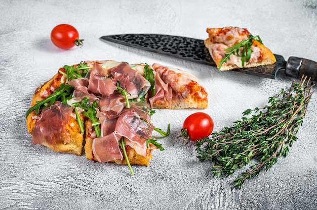 Italian Pizza with  parma ham, arugula and cheeseon a kitchen table. White background. Top view.