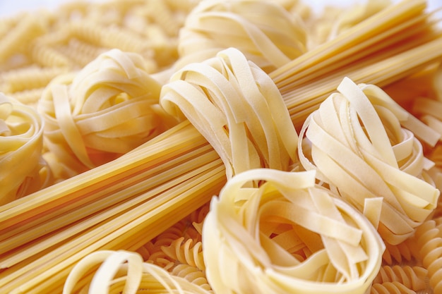 Italian rolled raw tagliatelle and spaghetti pasta