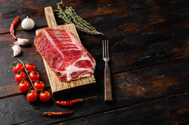 Italian sliced cured coppa with spices set, on old dark  wooden table background, with copy space for text