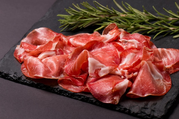 Italian slices of coppa, capocollo, capicollo or cured ham with rosemary. Raw food.