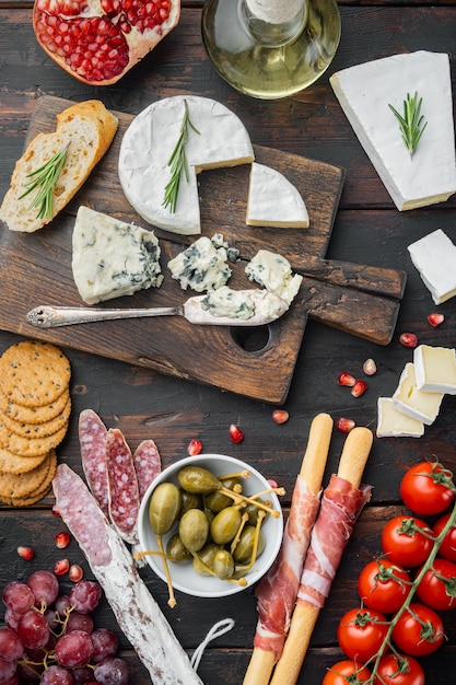 Italian snacks, meat cheese, herbs set, on dark wooden background, top view