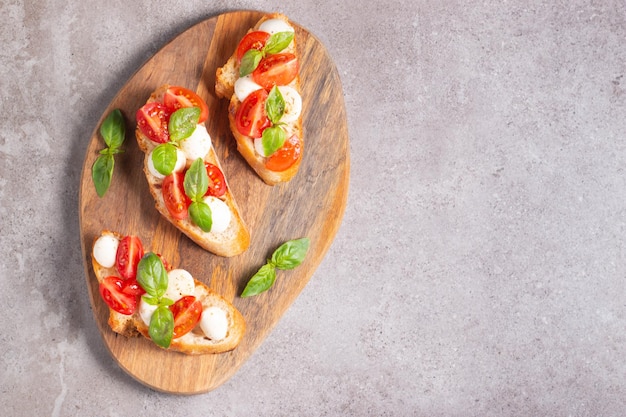 Italian tomato and cheese bruschetta Tapas antipasti with chopped vegetables herbs and oil on grilled ciabatta and baguette bread