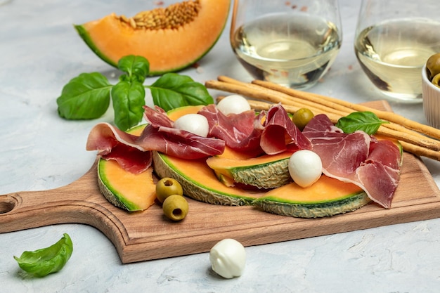 Italian traditional appetizer Prosciutto con Melone mozzarelle and basilico Cantaloupe melon with prosciutto or jamon mozzarella and green basil leaves