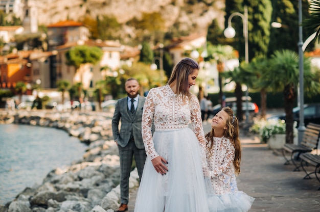 Photo italy, lake garda. beautiful family on the shores of lake garda in italy at the foot of the alps. father, mother and daughter in italy.