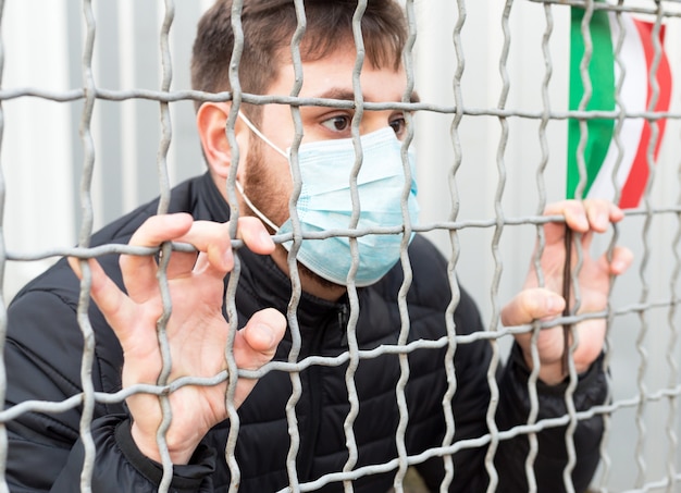 Italy quarantine, stop coronavirus. Italy coronavirus spreading outbreak. Covid-19 in Europe EU. Man in medical protective mask with Italian flag in cage