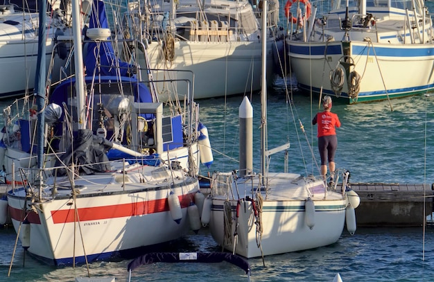 Italy, Sicily, Mediterranean sea, Marina di Ragusa (Ragusa Province); 8 February 2021, woman doing gymnastics and sailing boats in the port - EDITORIAL