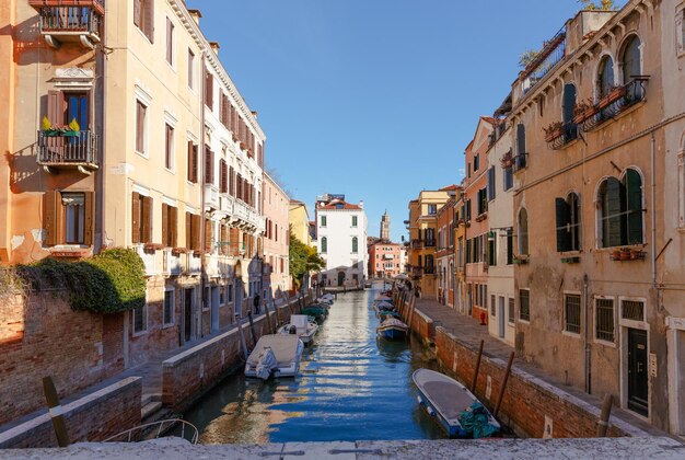 Italy Venice February 25 2017 Venice street with colorful houses lots of boats and a bridge sunny morning