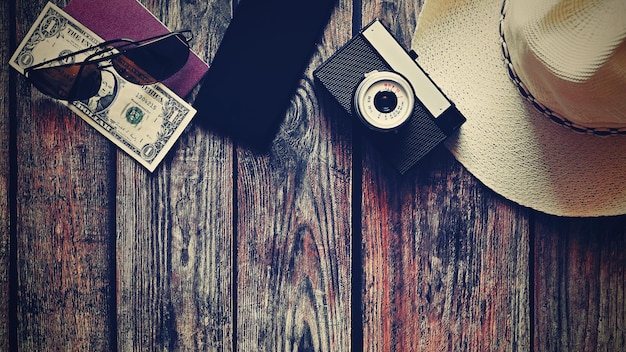 Items for summer vacation a camera passportsmartphone money hat sunglasses Wooden background top view with Copy space Beautiful summer concept for travel and summer vacation