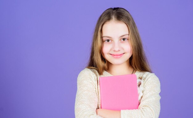 Its her favorite book Cute small child with text book in hands Adorable little girl holding exercise book Self study grammar book copy space