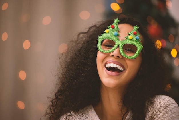 Its not just the Christmas tree that sparkles Portrait of a young woman fun glasses during Christmas at home