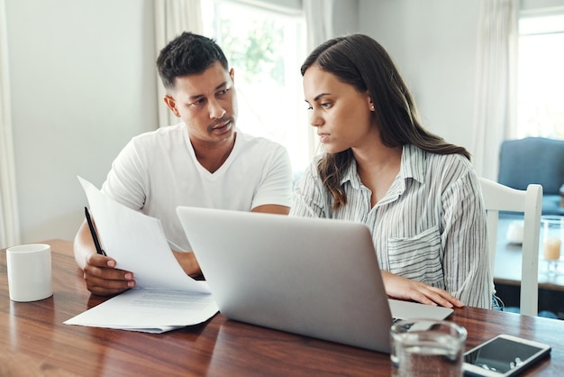 Its a numbers game Cropped shot of a young couple using a laptop to their household budget in the living room at home