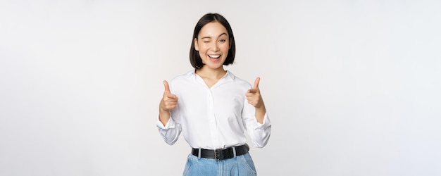 Its you congrats Smiling attractive asian woman businesswoman pointing fingers at camera with pleased face complimenting inviting you standing over white background