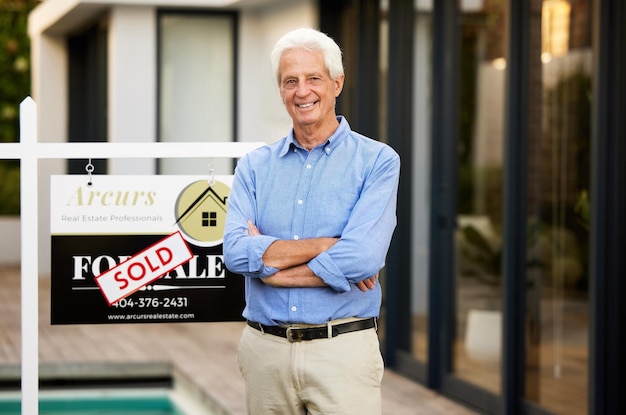 Ive found my own retirement home Cropped portrait of a handsome senior man standing with his arms crossed next to a sold sign outside of his newly purchased home