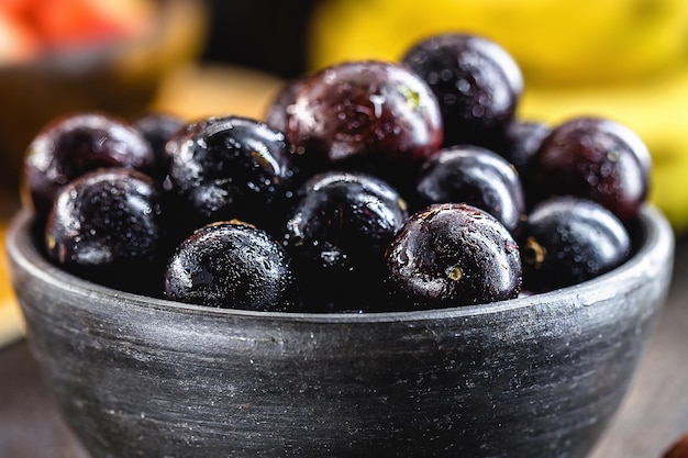 Photo jaboticaba or jabuticaba brazilian and south american fruit in a clay pot with tropical fruits in the background