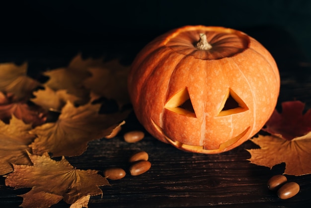 Jack lantern pumpkin for Halloween celebration with autumn orange maple leaves and acorns