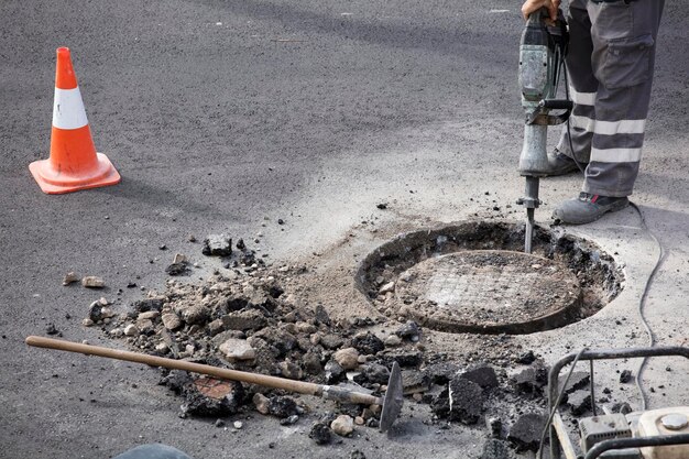 jackhammer in hands of asphalt worker logging underground and portable electric generator