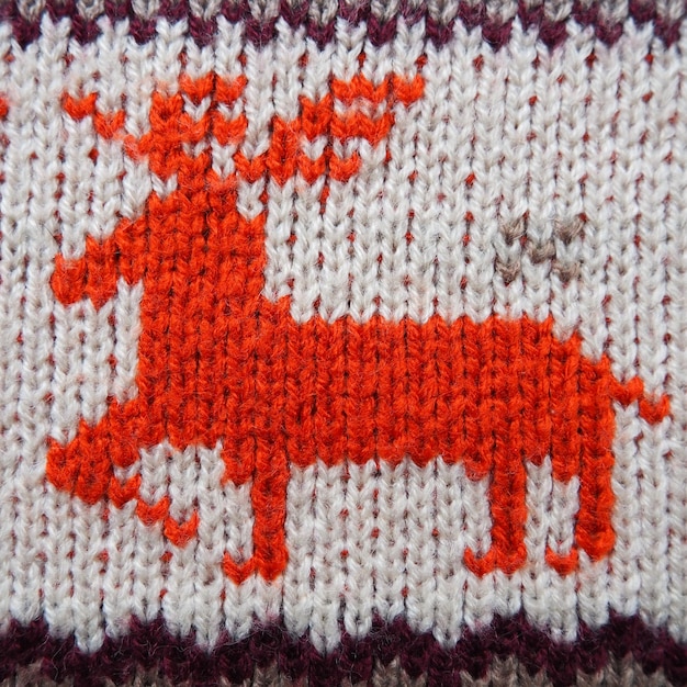 Jacquard knitted pattern Geometric ornament for Christmas or New Year Red deer on a white knitted background with horizontal zigzags Winter fashionable modern animal traditional folk ornament