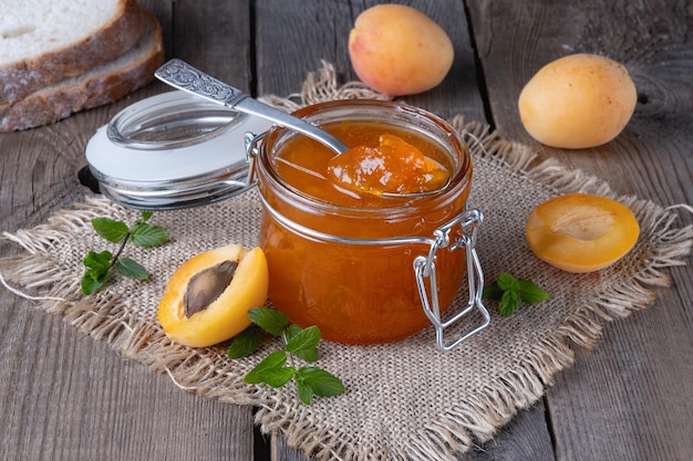 Jam from apricots in a glass jar on an old wooden table