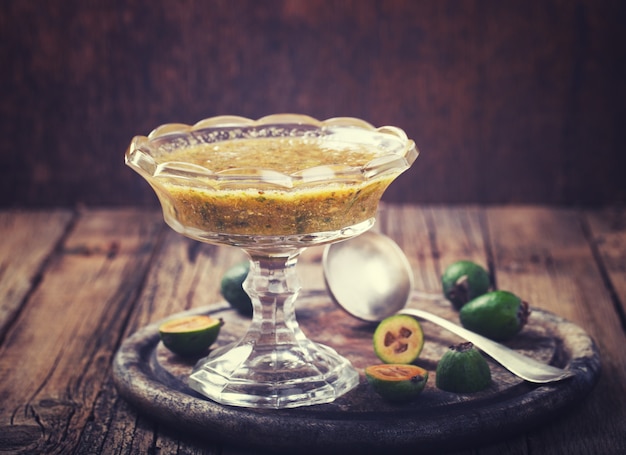 Jam from feijoa in a glass vase on a wooden Board.