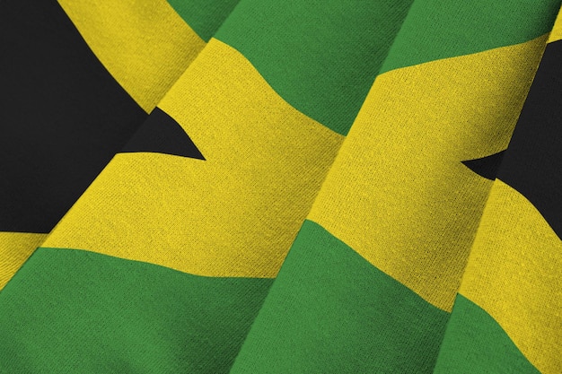 Jamaica flag with big folds waving close up under the studio light indoors The official symbols and colors in banner