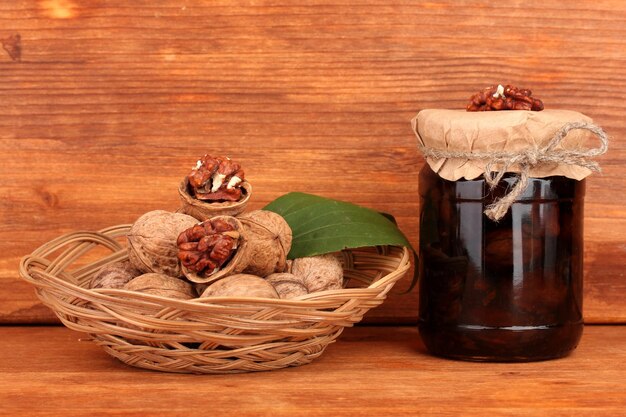 jamjar of walnuts and basket with walnuts on brown background