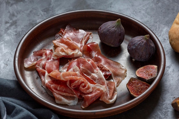 Jamon with figs and a baguette with cream cheese on the dining table appetizer for wine Spanish cooking