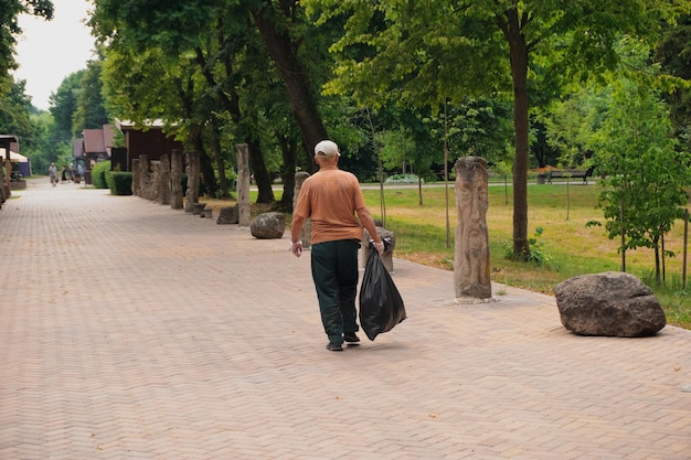 The janitor collects garbage in the park