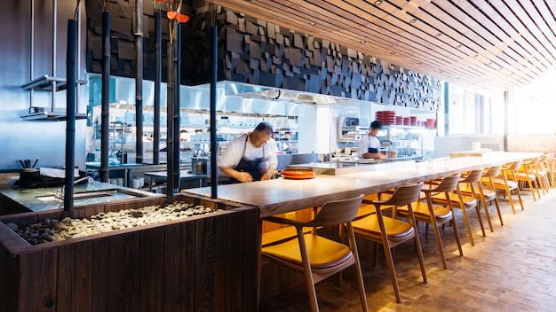 Japanese cooking counter with chefs making Omakase, sushi and sashimi in restaurant.