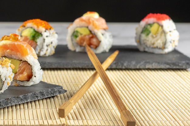 Japanese cuisine Sushi placed on a black plate accompanied by sauce and chopsticks Selective focus