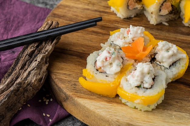 Japanese cuisine. Sushi roll with mango and crab in wooden plate