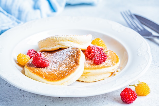 Japanese fluffy pancakes with raspberries in a white plate, white background. Japanese cuisine concept.