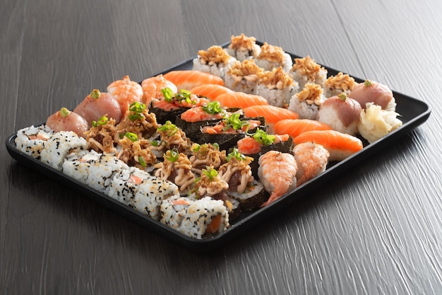 Japanese food combo and crispy onions served in restaurant on black plate on wooden table