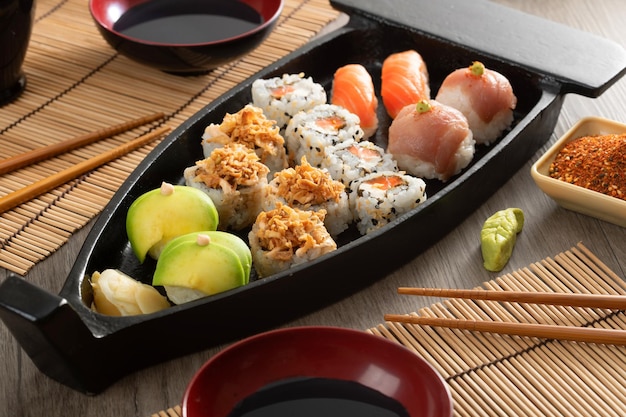 Japanese food and crispy onions served in restaurant on black boat on wooden table