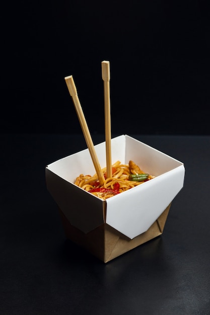 Japanese food, wok udon noodles with meat and vegetables in an open box isolated on a solid background.