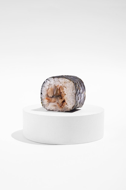 Japanese hosomaki sushi rolls with eel on a white plaster stand on a white plain background