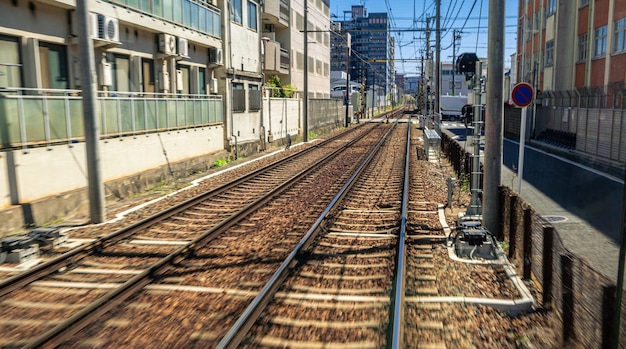 Japanese Kyoto local train traveling on rail tracks along the railway at spring season. Scene of railroad and train travels landscape. Transport for sightseeing Japan concept