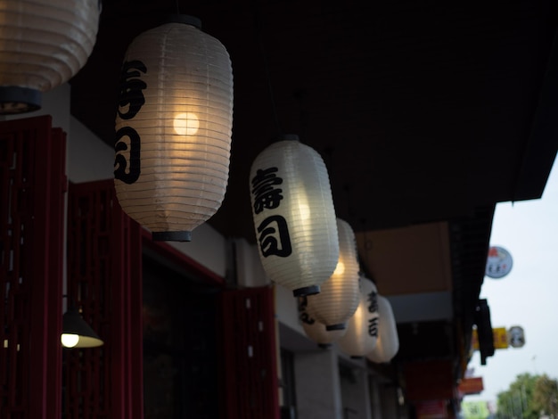 Japanese lantern hung in front of Japanese Restaurant Japanese text on lantern is Sushi.