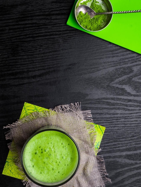 Japanese matcha green powdered tea latte served in glass on sackcloth powder in bowl with vintage spoon copy space