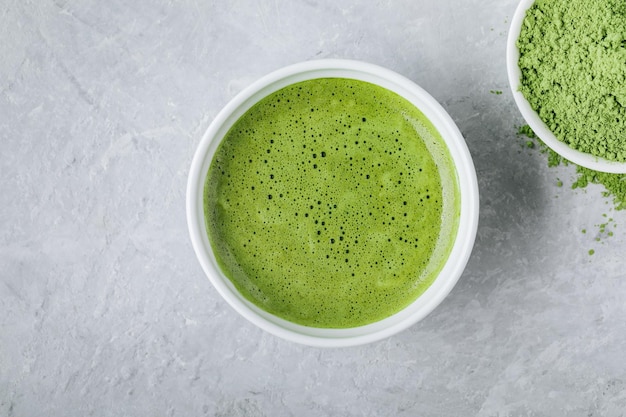 Japanese matcha green tea latte in white bowl on gray stone background Top view